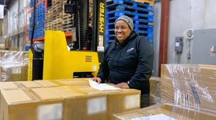 Warehouse staff applying UCC-128 compliance labels and price tags to retail master cases